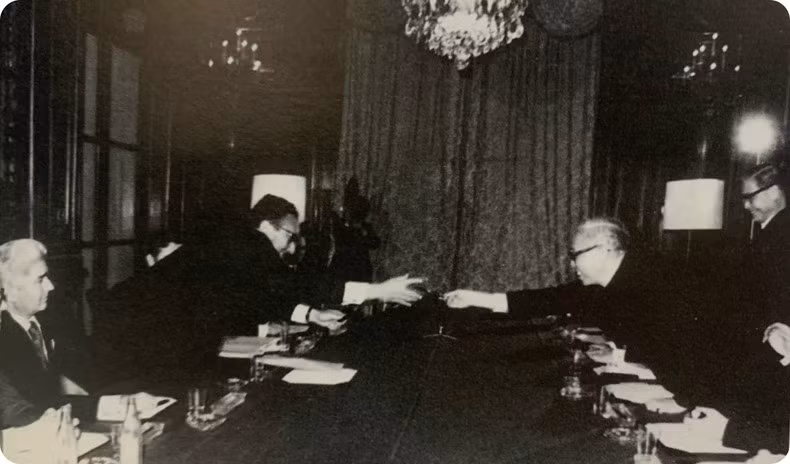 Le Duc Tho y Henry Kissinger intercambian bolígrafos después de firmar los acuerdos.