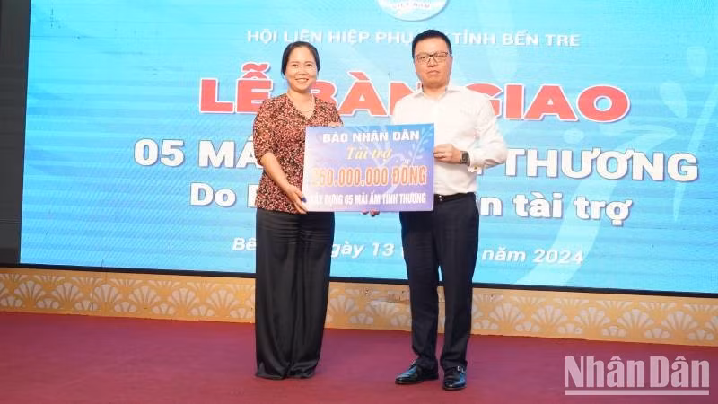 El presidente-editor de Nhan Dan, Le Quoc Minh, entrega un simbólicamente el apoyo a la Unión de Mujeres de la provincia de Ben Tre.
