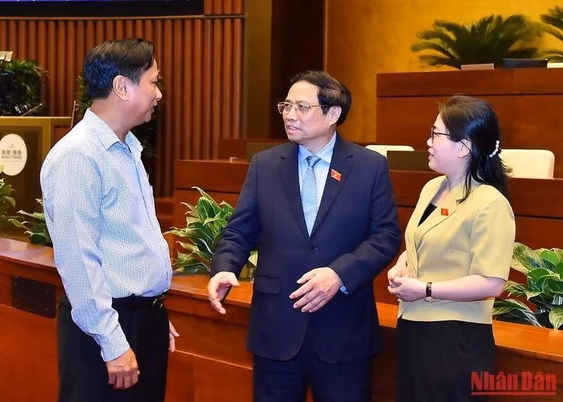 El primer ministro Pham Minh Chinh expresa sus opiniones con los delegados al margen de la reunión.