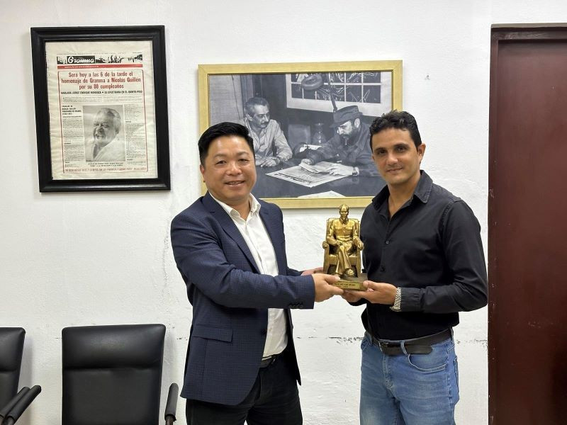 Que Dinh Nguyen, subjefe del periódico Nhan Dan, entrega un regalo de recuerdo a Dilbert Reyes, subdirector editorial del diario Granma.