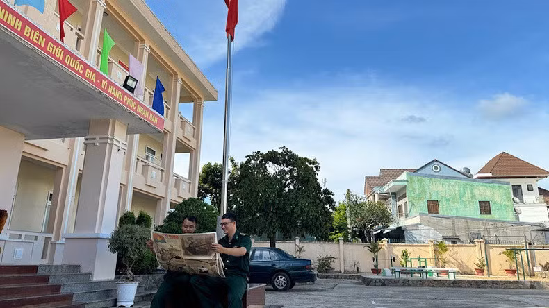 El teniente mayor Nguyen Van Duc, jefe del equipo de movilización de masas, lee el suplemento bajo la bandera nacional.