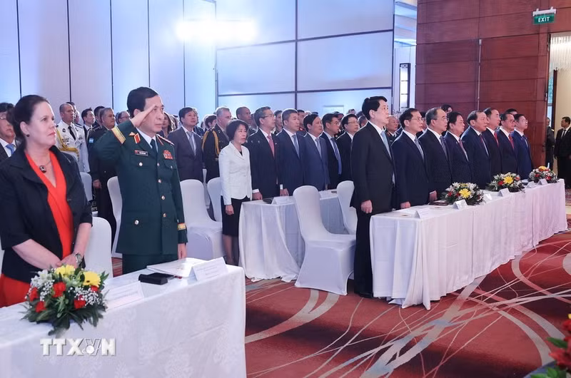 Los asistentes saludan a la bandera nacional.