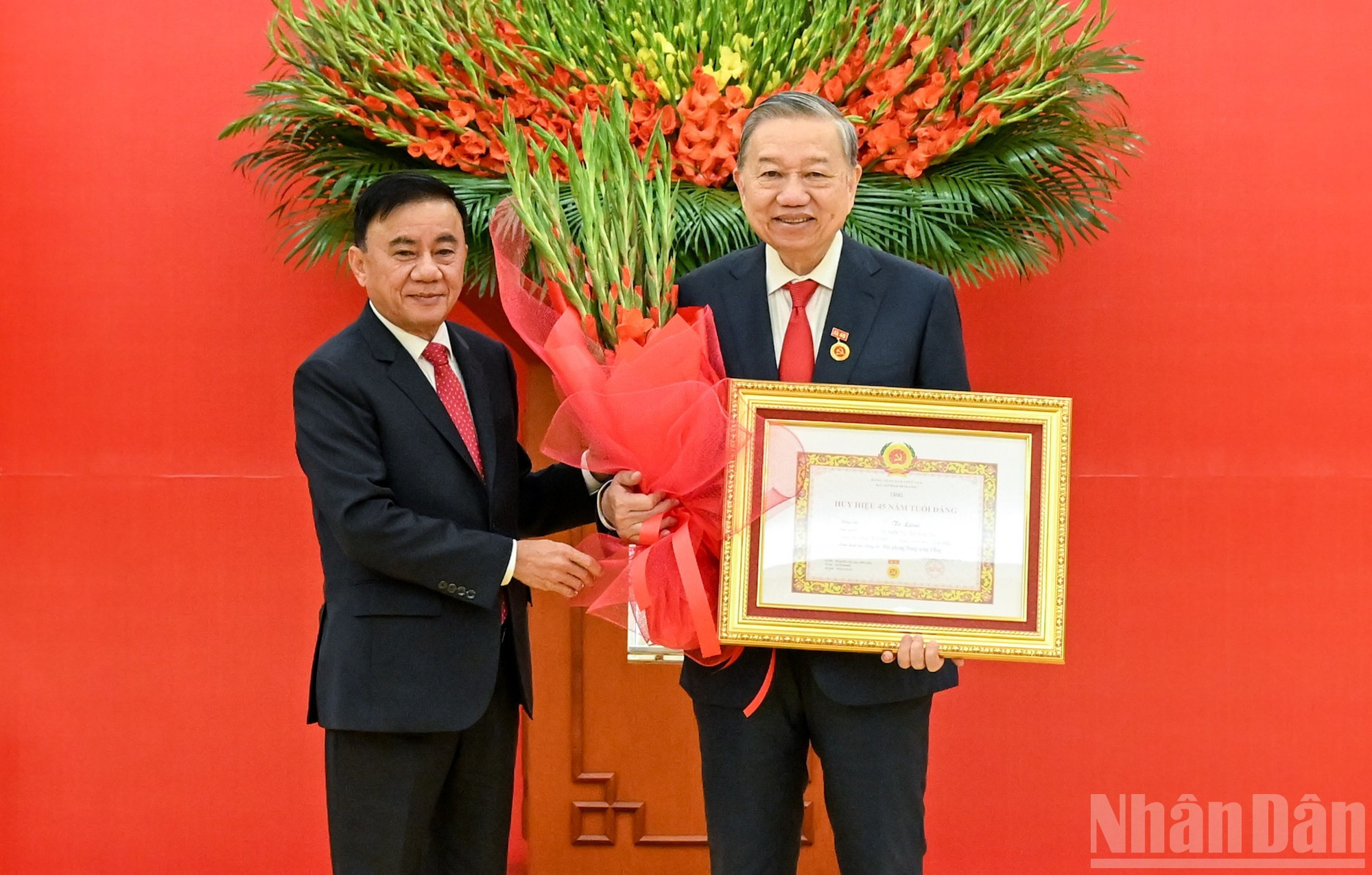 El integrante del Buró Político y miembro permanente del Secretariado del Comité Central del Partido, Tran Cam Tu, entrega flores de felicitación al secretario general del Partido, To Lam.
