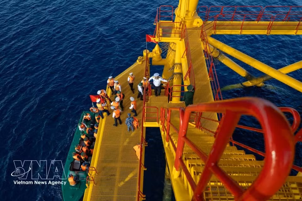 Un barco de trabajo se aproxima a las plataformas en condiciones marítimas favorables.