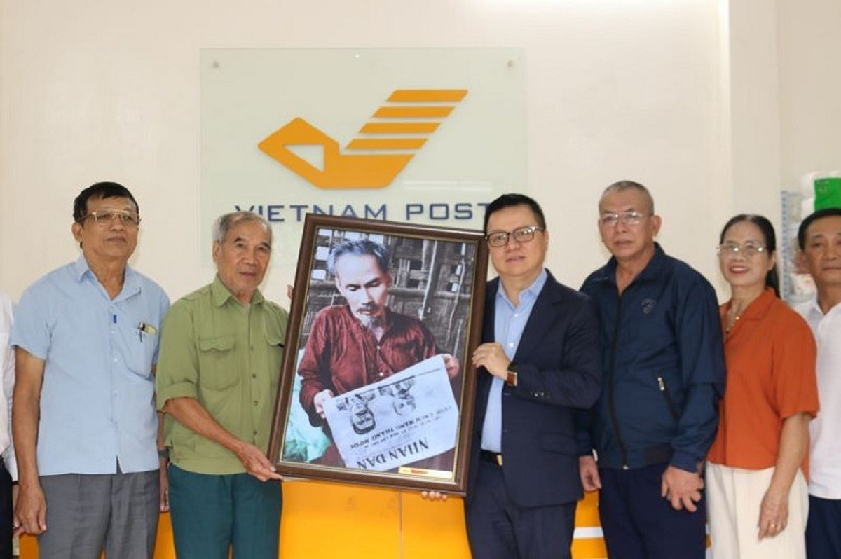 El compañero Le Quoc Minh entrega la pintura “El Tío Ho lee el periódico Nhan Dan” a la Oficina de Correos combinada con el modelo de casa comunal de Bat Trang. image-2-9456.jpg