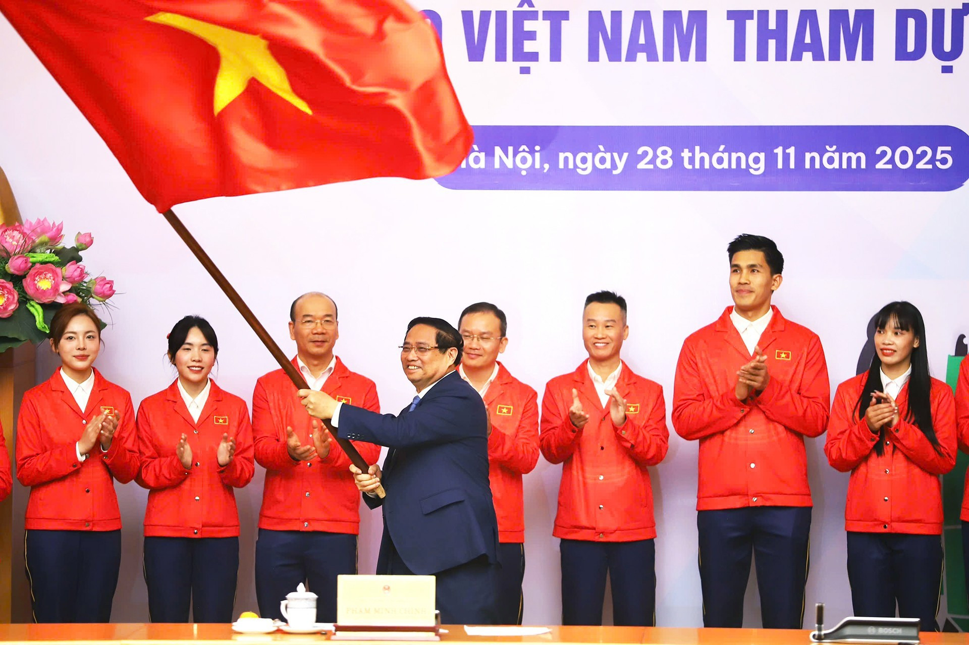 El jefe de Gobierno entrega la bandera nacional a la delegación.