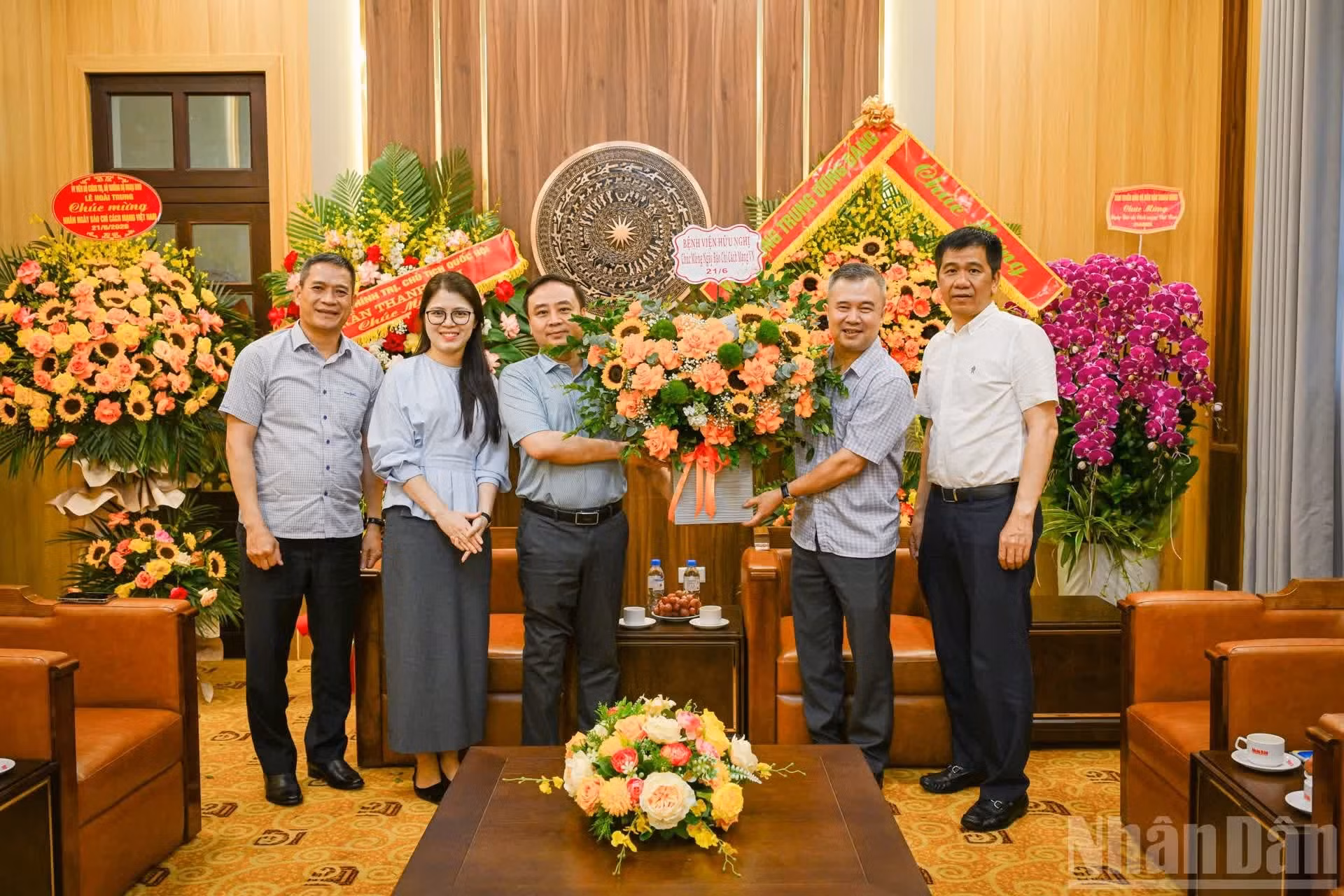 El doctor Bui Long, vicedirector del Hospital de Amistad (Hanói), entrega flores de felicitación por el 21 de junio a los empleados de Nhan Dan.