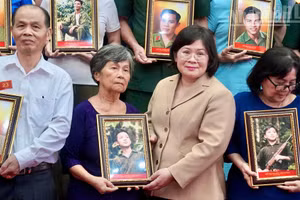 Van Thi Bach Tuyet, vicesecretaria del Comité del Partido Comunista de Vietnam en Ciudad Ho Chi Minh, entrega retratos restaurados de combatientes caídos a sus familiares. (Foto: Nhan Dan)