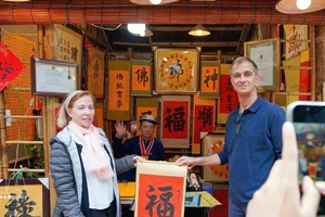 Los turistas internacionales disfrutan de la tradición de recibir caligrafía auspiciosa a principios de año. (Foto: VNA)
