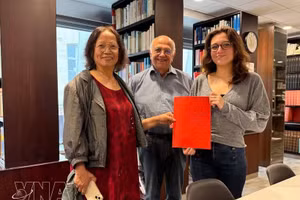 La investigadora cultural Tran Thu Dung (izquierda), Yonnel Ghernaouti, miembro de la Junta Directiva del Instituto Masónico de Francia, y Emma Lallemand, bibliotecaria del GODF, posan para una fotografía con documentos de archivo sobre Nguyen Ai Quoc. (Foto: VNA)