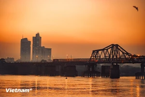 Desde la distancia, se puede contemplar el puente Long Bien, donde el atardecer tiñe el agua de carmesí mientras un tren avanza lentamente hacia el corazón de la ciudad. (Foto: Vietnam+)