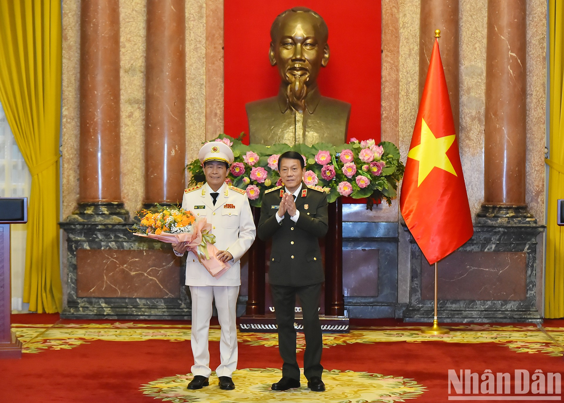 El ministro de Seguridad Pública, Luong Tam Quang, entrega flores para felicitar al teniente general Le Quoc Hung.