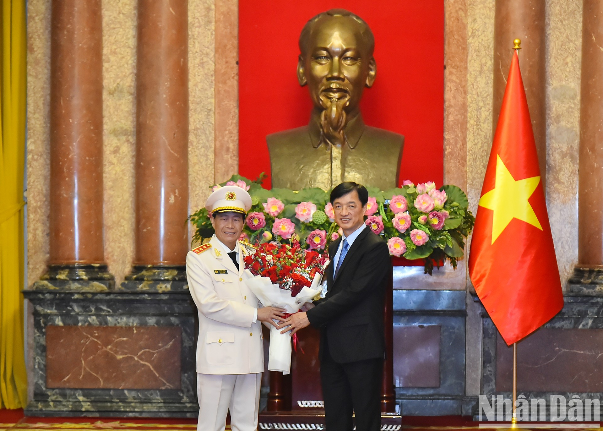 El jefe de la Oficina Central del Partido, Nguyen Duy Ngoc, entrega flores para felicitar al teniente general Le Quoc Hung.