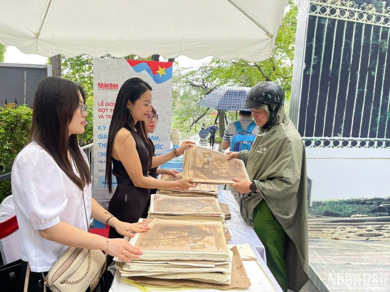Muchos lectores llegan desde lejos bajo la lluvia para recibir la publicación informativa especial de Nhan Dan.