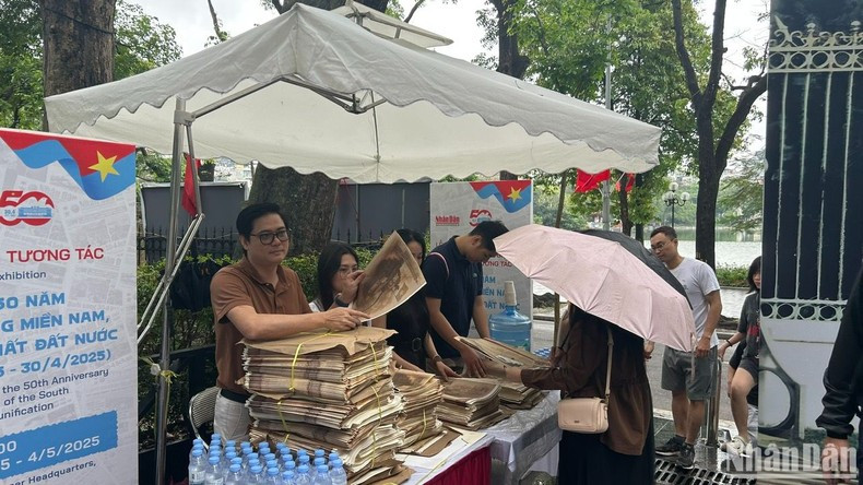 Muchos lectores llegan temprano para recibir la publicación, a pesar de la fuerte lluvia.