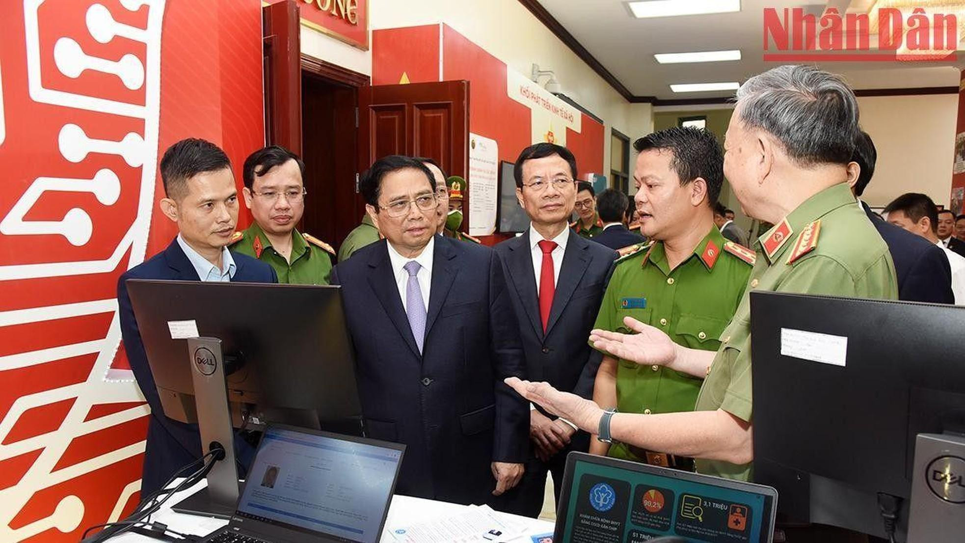 El jefe del Gobierno Pham Minh Chinh y otros delegados observan productos tecnológicos de transformación digital.