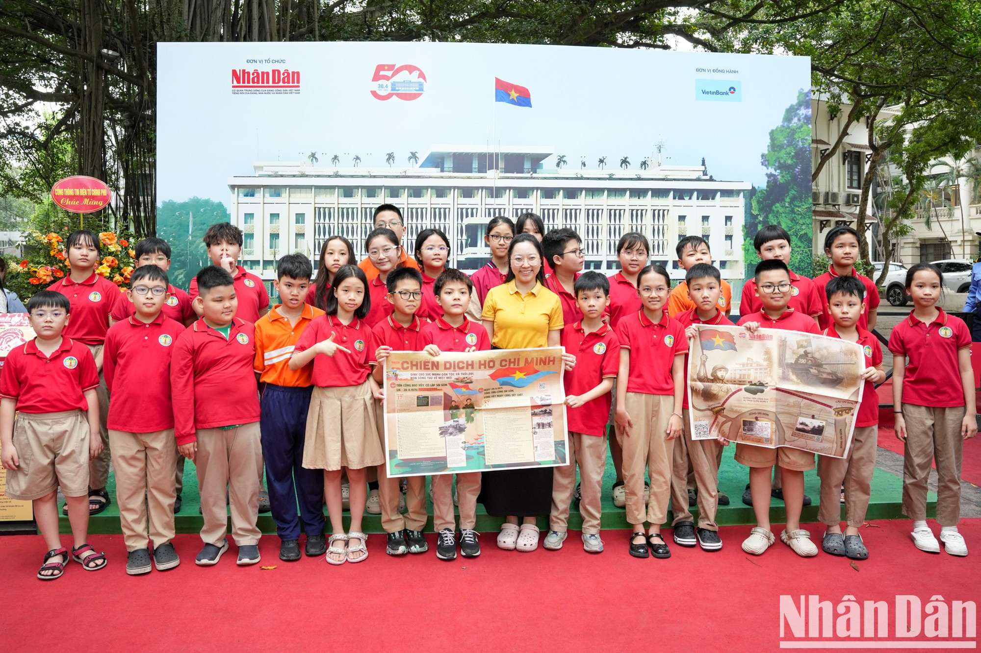 Maestra y alumnos de la escuela primaria Trang An se toman fotografías con una publicación informativa especial del periódico Nhan Dan.