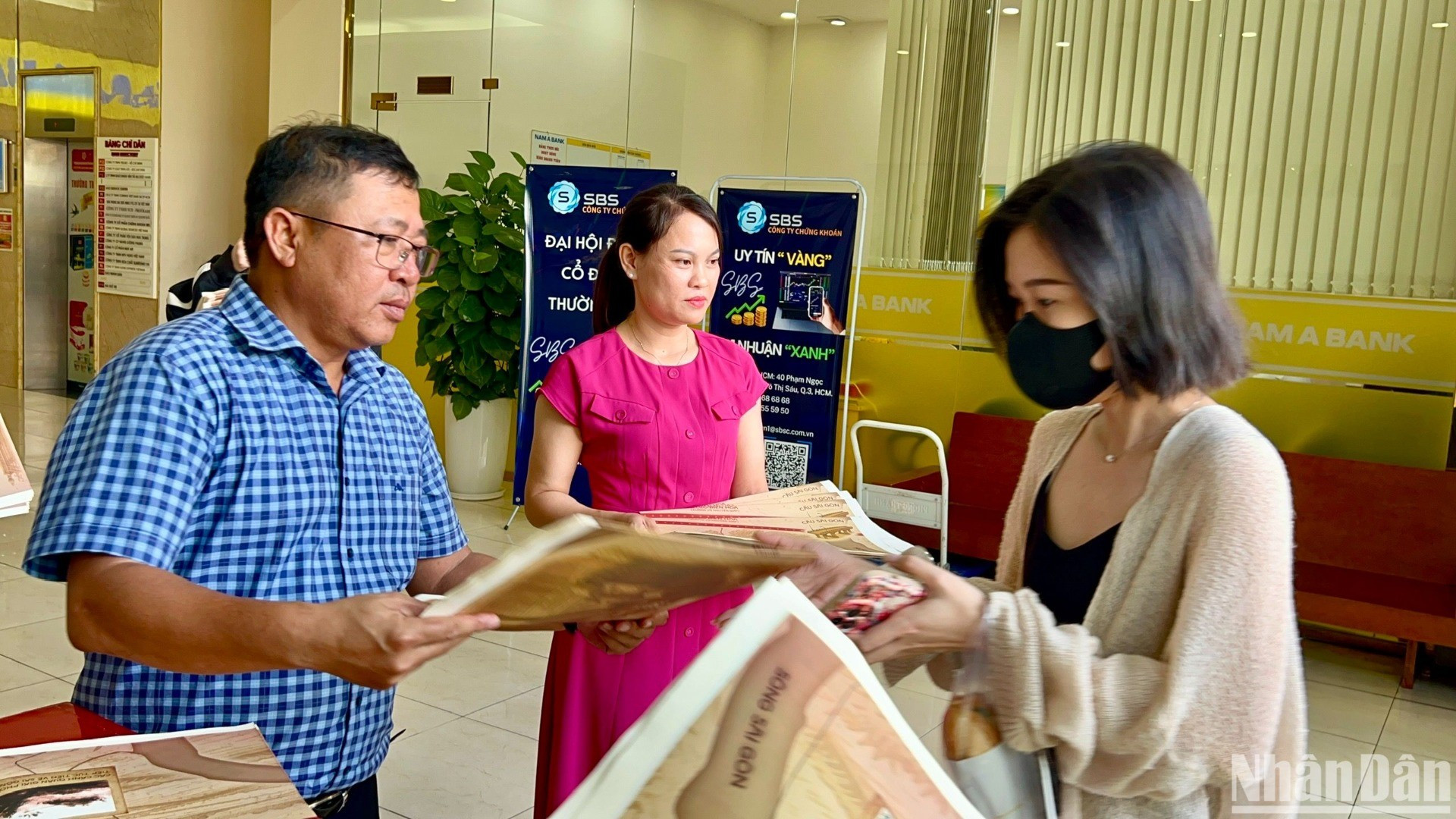 Representantes de la corresponsalía en el Sur del periódico Nhan Dan entregan suplementos especiales a los lectores.