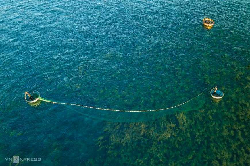 Una pareja local pesca sobre las algas verdes.
