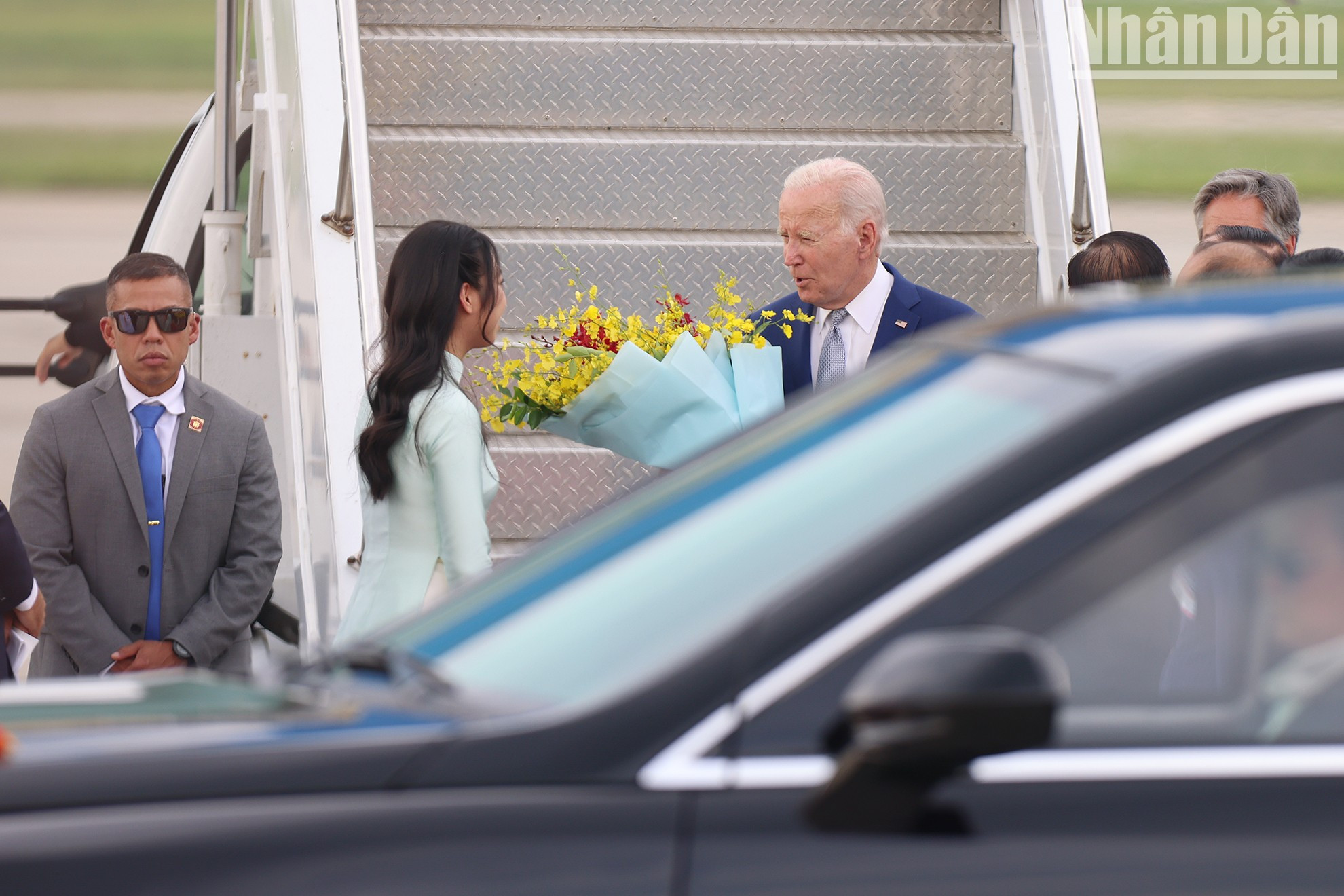 Una jóven hanoyese entrega flores para dar la bienvenida al presidente Joe Biden.