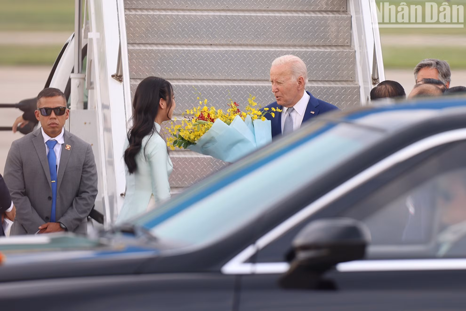 Una jóven hanoyese entrega flores para dar la bienvenida al presidente Joe Biden.