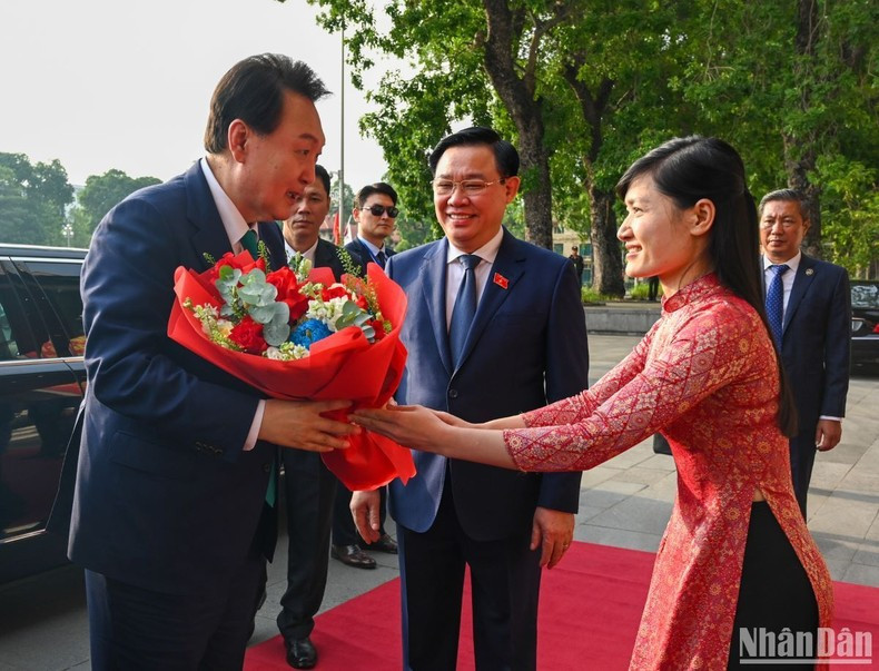 Miembro de la Oficina de la Asamblea Nacional de Vietnam entrega flores para dar la bienvenida al visitante surcoreano.