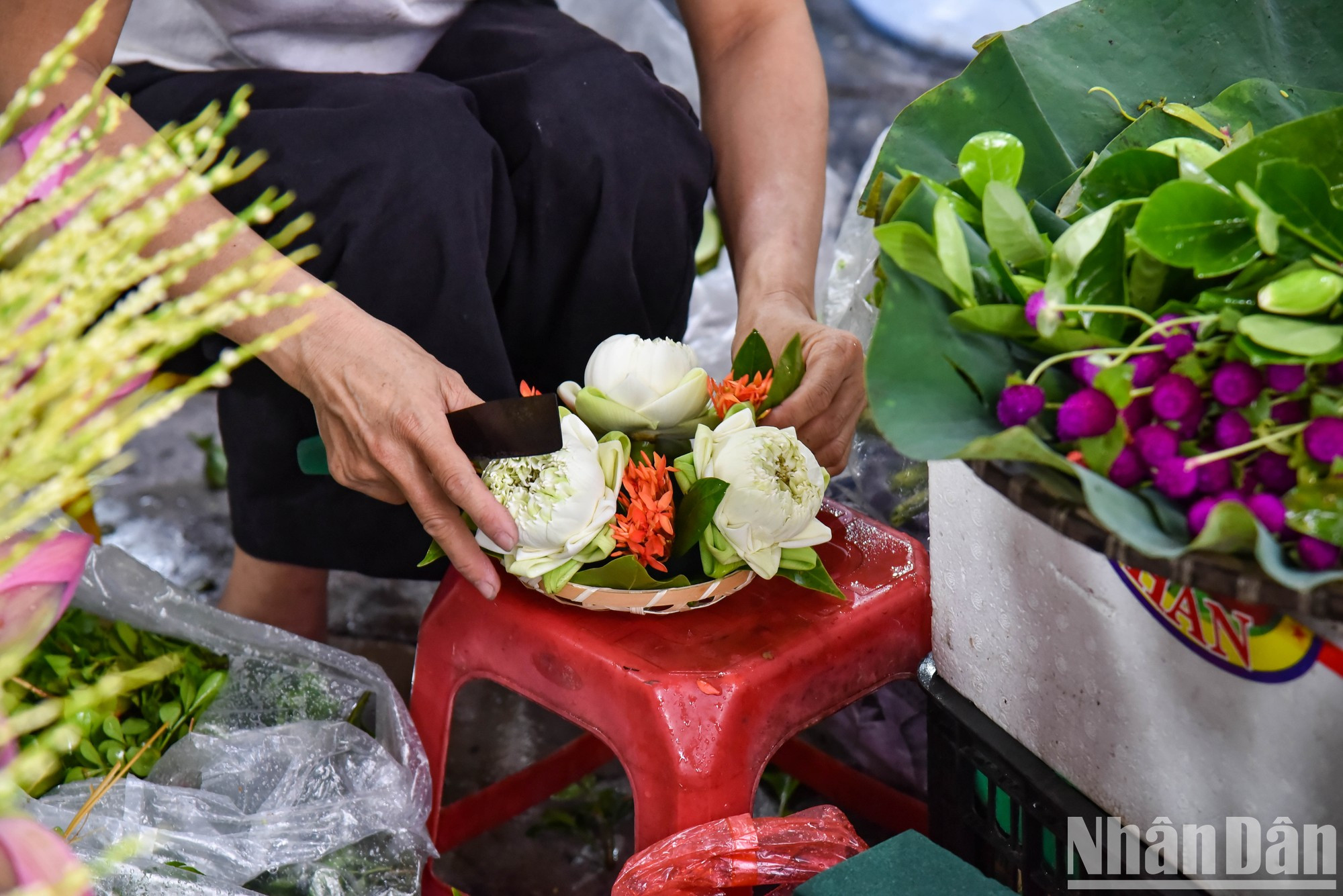 Un vendedor prepara meticulosamente bandejas florales en las que suele haber loto, flor de areca, ylang ylang y azucenas. Un vendedor prepara meticulosamente bandejas florales en las que suele haber loto, flor de areca, ylang ylang y azucenas.