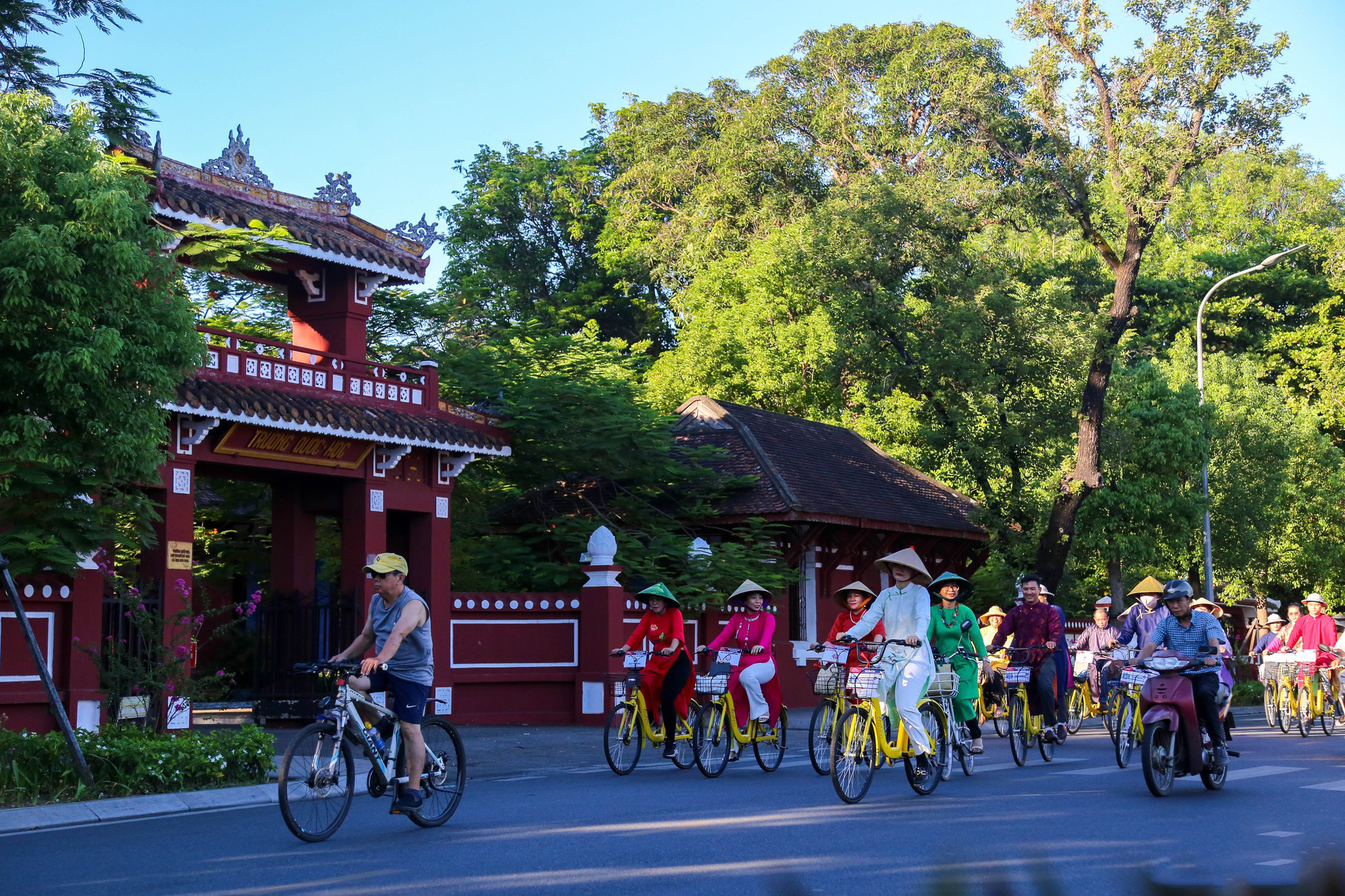 Un grupo de ciclistas desfilan frente a la escuela Quoc Hoc Hue.