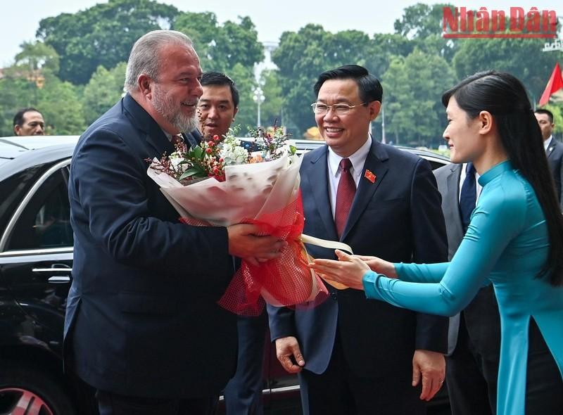 Empleada de la Oficina de la Asamblea Nacional de Vietnam entrega flores para dar la bienvenida al primer ministro cubano, Manuel Marrero Cruz.
