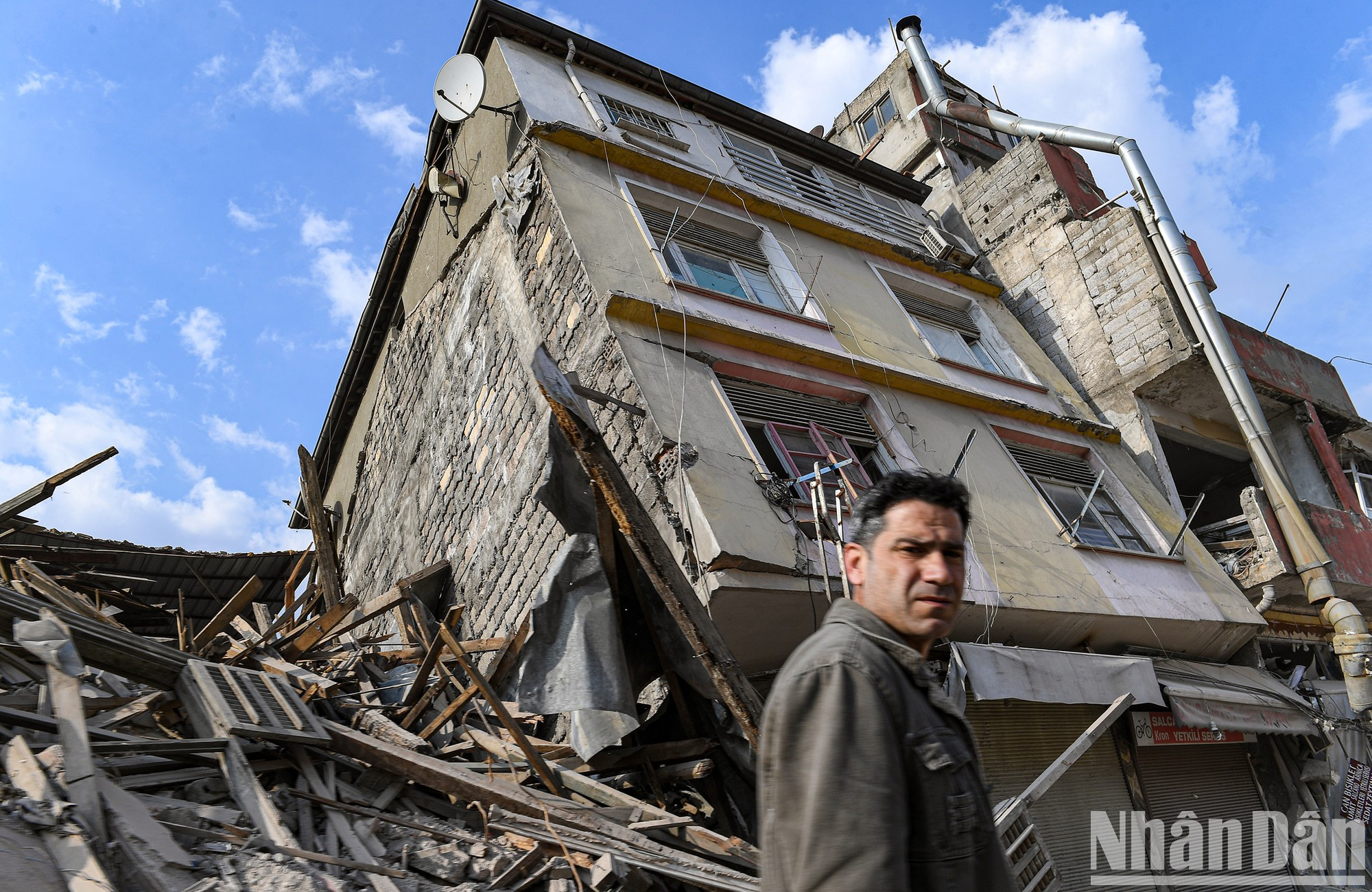 Detrás de este hombre está un edificio completamente colapsado. Al pasar por donde una vez estuvo su hogar, el hombre no puede ocultar su preocupación por el futuro. Detrás de este hombre está un edificio completamente colapsado. Al pasar por donde una vez estuvo su hogar, el hombre no puede ocultar su preocupación por el futuro.