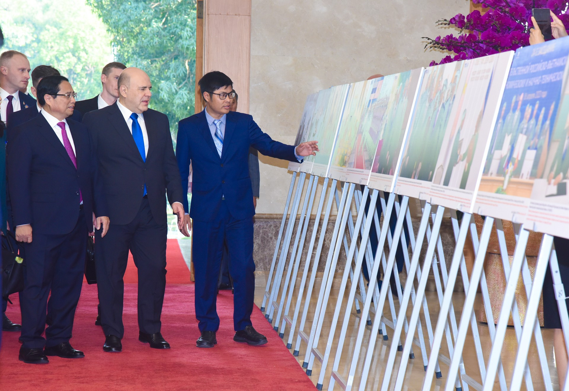 El jefe de Gobierno vietnamita enseña a su par ruso una exhibición de imágenes sobre las relaciones binacionales.