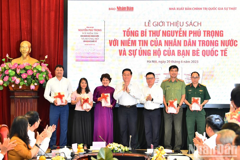 El jefe de la Comisión de Comunicación y Educación del Comité Central del Partido Comunista de Vietnam, Nguyen Trong Nghia (centro), y el presidente-editor de Nhan Dan, Le Quoc Minh, entregan ejemplares del libro a delegados de algunas instituciones, localidades, escuelas y bibliotecas.