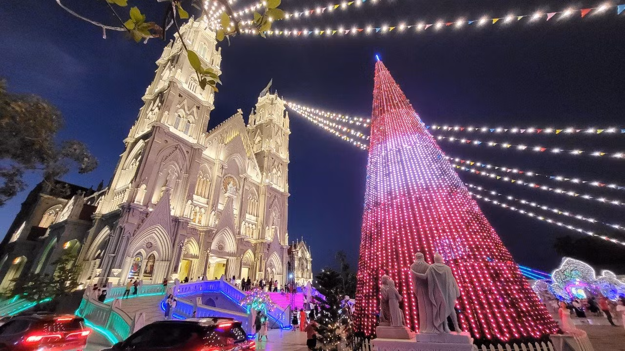 El árbol de Navidad instalado frente a la iglesia animado con muchas luces.