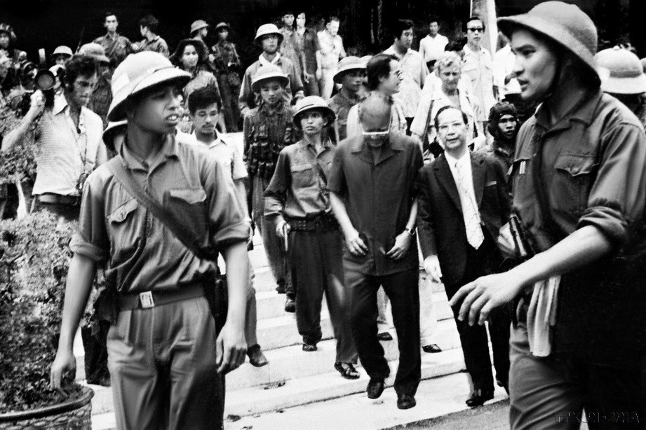 El capitán Pham Xuan The (derecha), subcomandante del Regimiento 66, División 304 (Cuerpo de Ejército 2), junto con los combatientes del Ejército de Liberación, escoltan al presidente Duong Van Minh y al primer ministro Vu Van Mau del régimen títere de Saigón hacia la emisora de radio para leer la declaración de rendición incondicional.