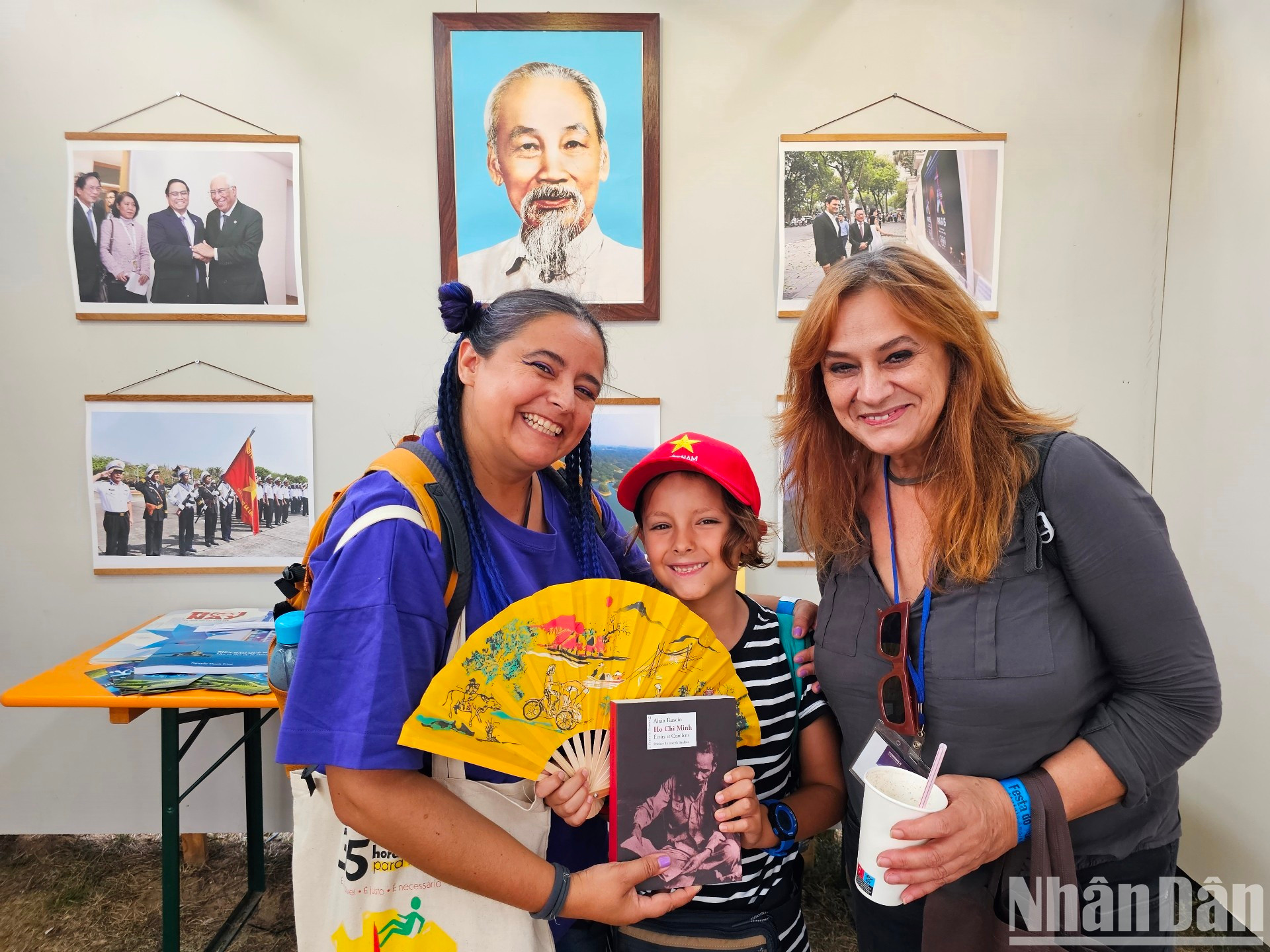 Ana Mesquita (izquierda), su madre y su hijo, emocionados al posar con un retrato del Presidente Ho Chi Minh en el fondo y recibir libros sobre el eminente líder. “Vinimos en cuanto divisamos desde lejos la bandera de Vietnam. Debido a la lejanía entre los dos países no estaba al tanto del desarrollo de Vietnam, así que me alegré al enterarme de sus cambios tan positivos mediante el evento”.