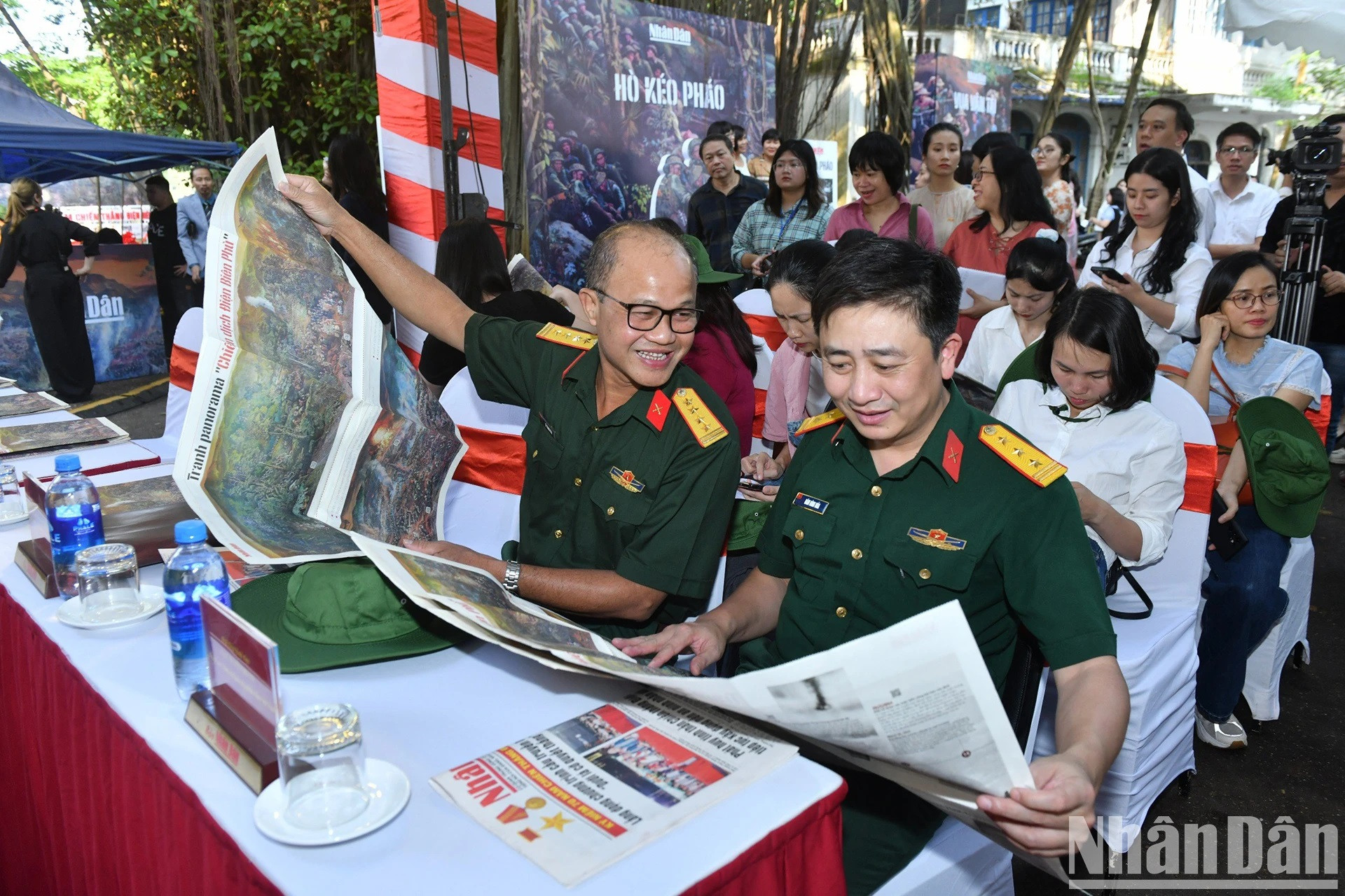 Los delegados observan el suplemento de Nhan Dan con dicha pintura panorámica.