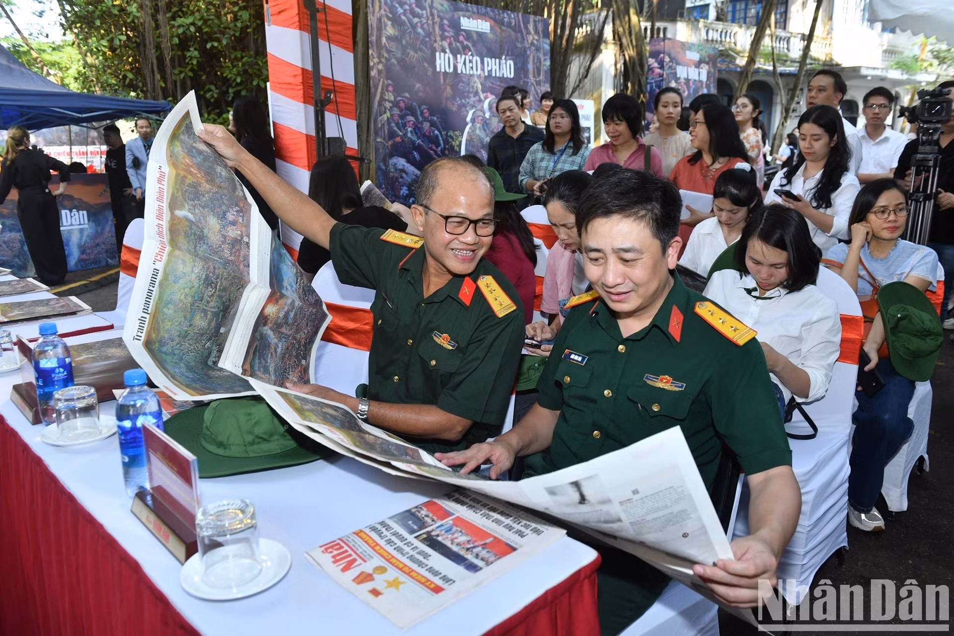 Los delegados observan el suplemento de Nhan Dan con dicha pintura panorámica.