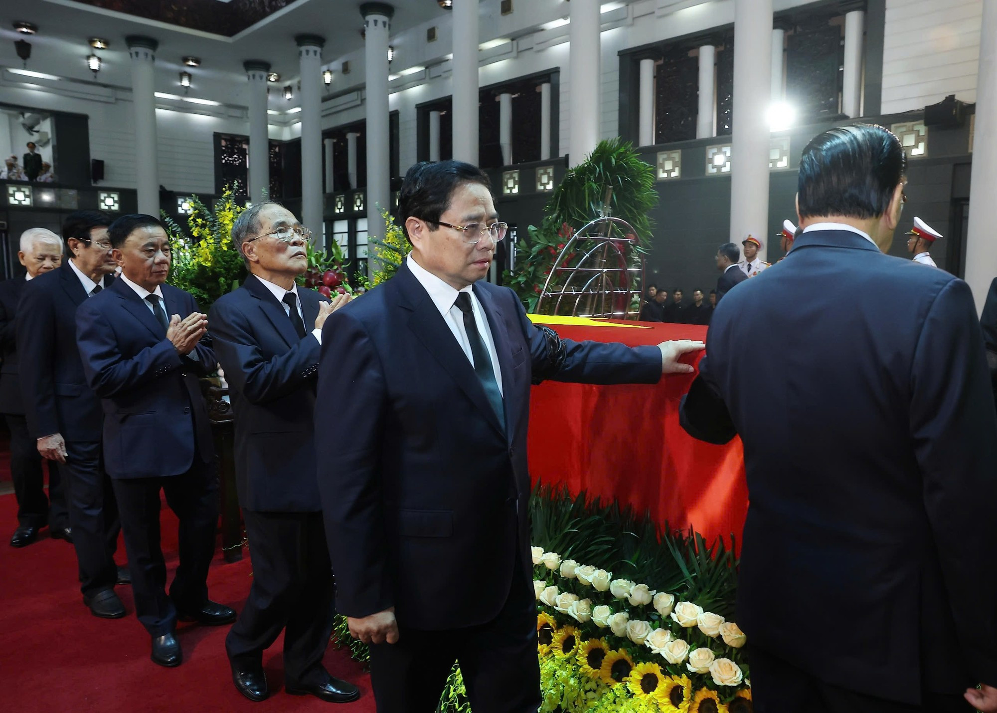 Los miembros de la delegación rinden tributo al extinto.