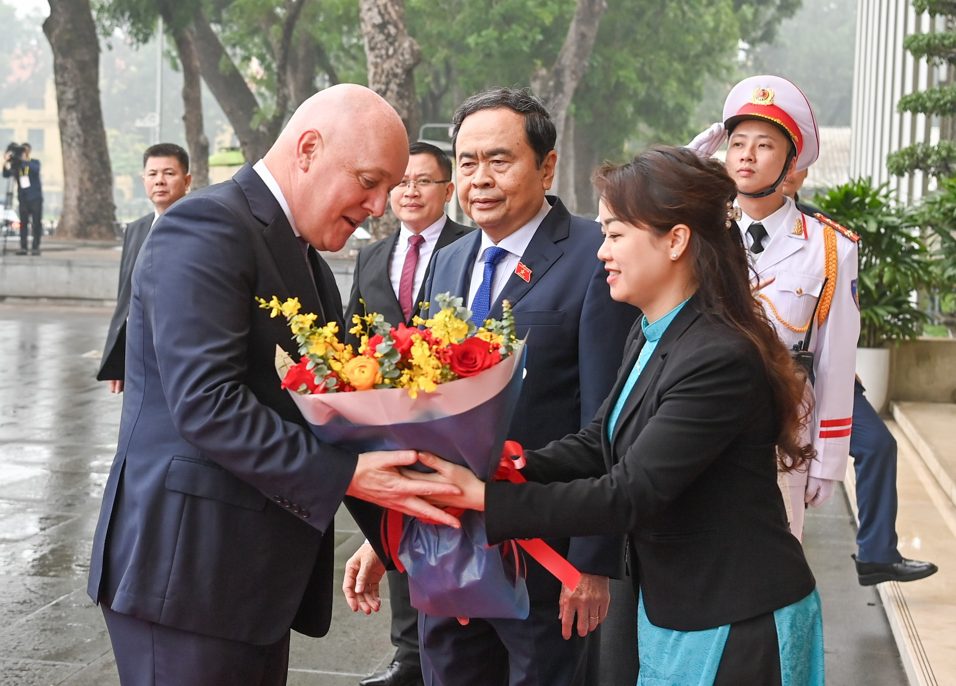 Una empleada de la Casa Parlamentaria, sede de la Asamblea Nacional anfitriona, entrega flores de bienvenida al jefe de Gobierno neozelandés. Una empleada de la Casa Parlamentaria, sede de la Asamblea Nacional anfitriona, entrega flores de bienvenida al jefe de Gobierno neozelandés.