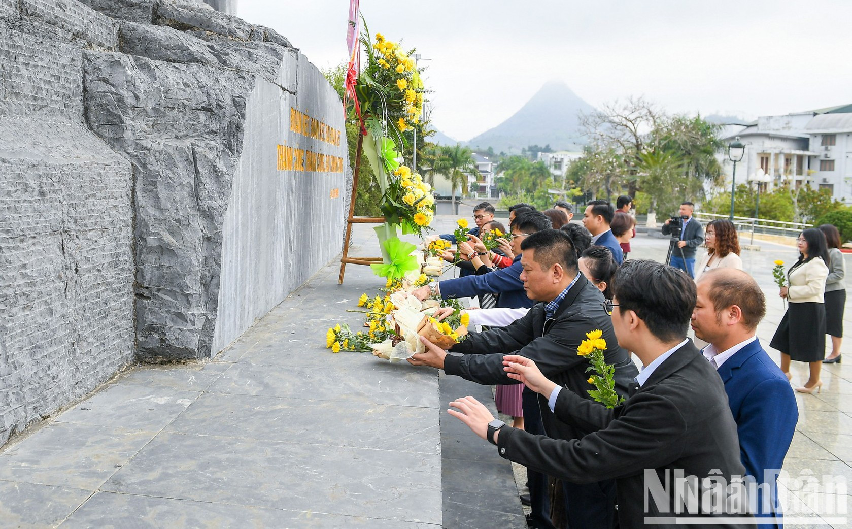 Participantes colocan flores ante el monumento.