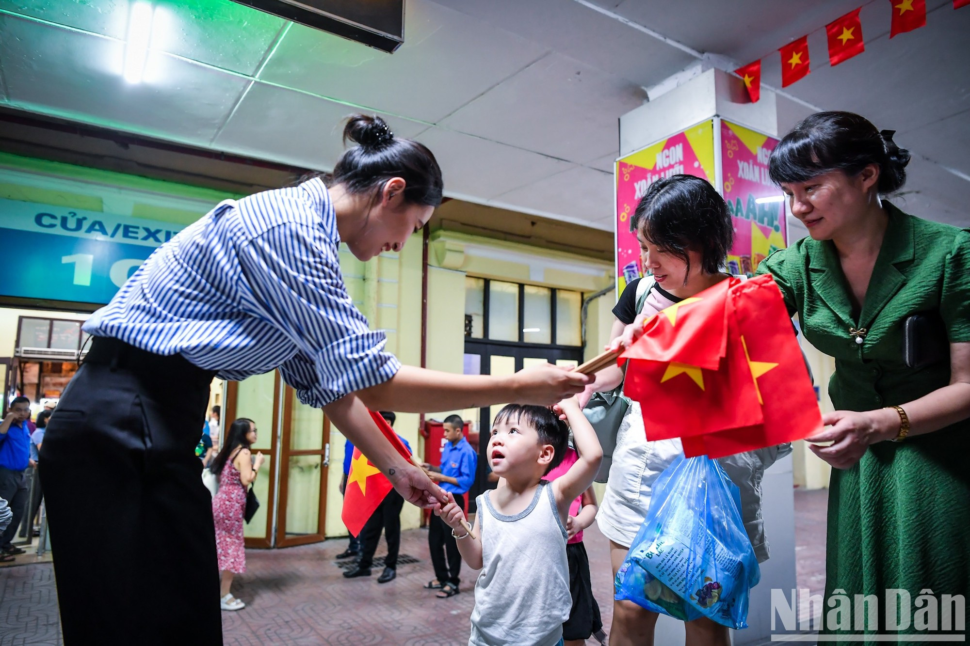Los pasajeros reciben banderitas nacionales en la estación de Hanoi antes de embarcar.