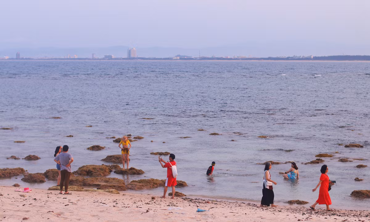 Desde tierra firme los visitantes pueden ver claramente la isla verde de arena blanca, rodeada de barcos pesqueros anclados cerca de la orilla.