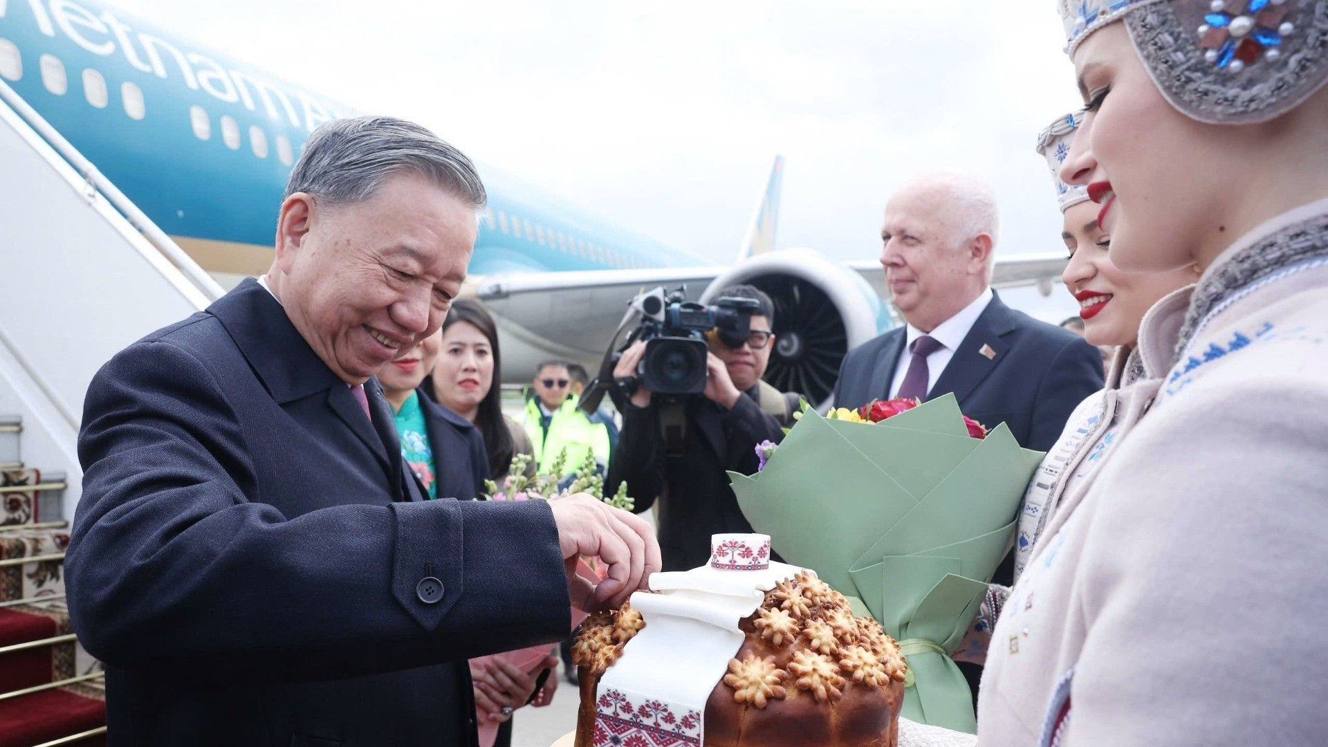 Las muchachas bielorrusas con trajes tradicionales invitan respetuosamente al secretario general To Lam a disfrutar de pan y sal según el ritual bielorruso de bienvenida a invitados distinguidos. (Foto: VNA)