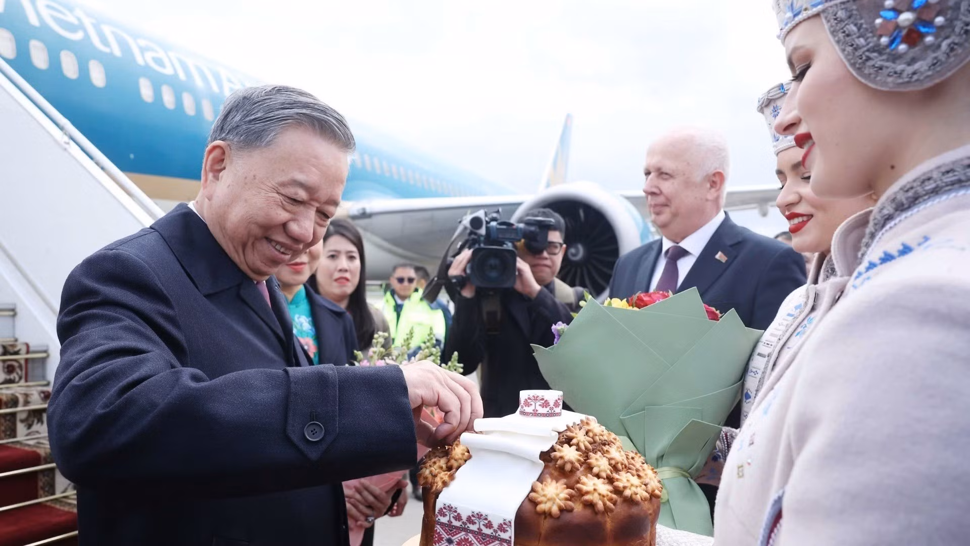 Las muchachas bielorrusas con trajes tradicionales invitan respetuosamente al secretario general To Lam a disfrutar de pan y sal según el ritual bielorruso de bienvenida a invitados distinguidos. (Foto: VNA)