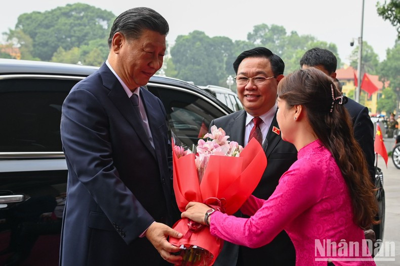 Xi Jinping recibido por una vietnamita con flores.
