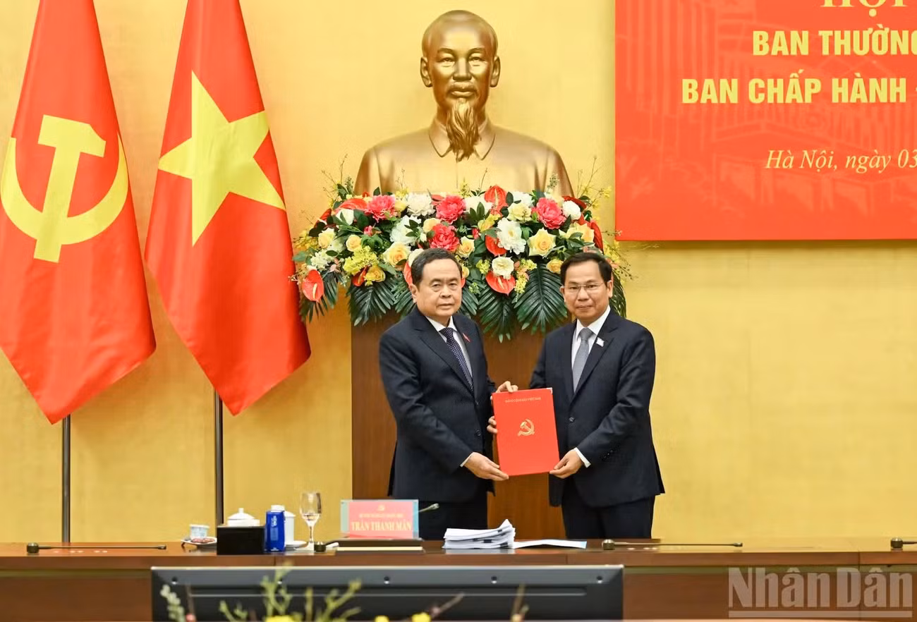 El secretario del Comité del Partido Comunista de Vietnam en la Asamblea Nacional y presidente de esta, Tran Thanh Man (izquierda), entrega la decisión del Buró Político del Comité Central del Partido a Le Quang Manh.