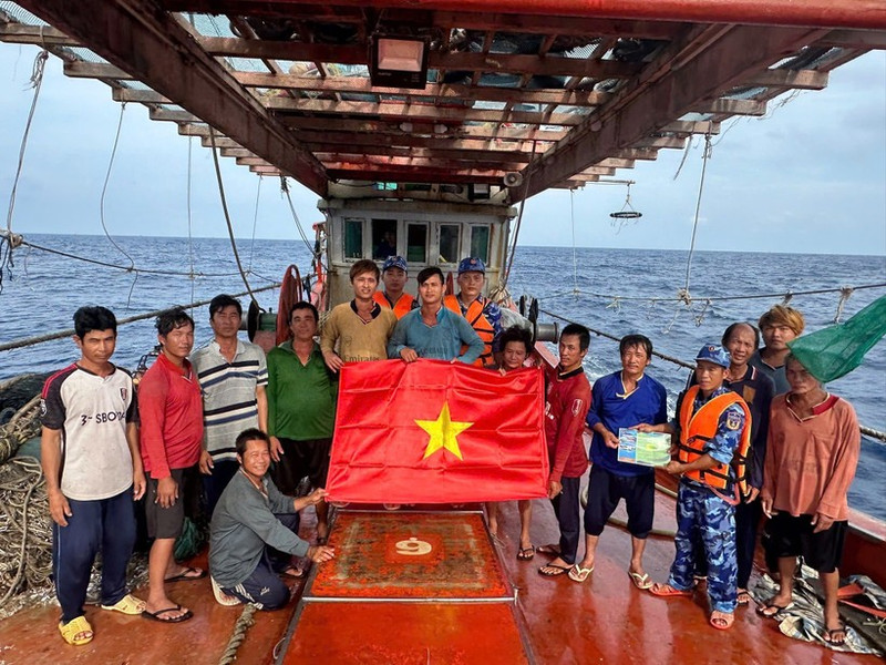 Las fuerzas de seguridad marítima de Ciudad Ho Chi Minh entregan la bandera nacional y difunden medidas preventivas contra la pesca INDNR a los marineros. (Foto: VNA)