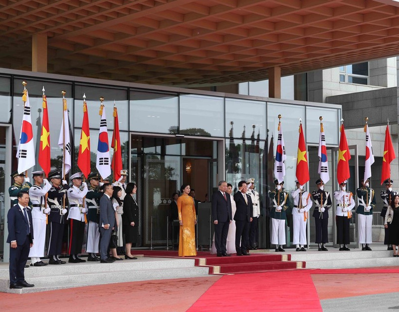 El presidente de Corea del Sur, Lee Jae Myung, y su esposa, junto con el secretario general del Partido Comunista de Vietnam, To Lam, y su cónyuge, en posición de honor, escuchan a la banda militar interpretar los himnos nacionales de sus países. (Foto: VNA)