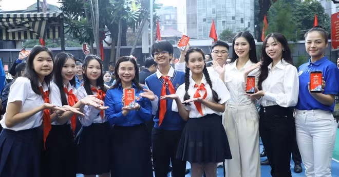 Jóvenes escanean códigos QR para instalar un conjunto especial de fondos de pantalla con el tema "La juventud vietnamita da la bienvenida al XIV Congreso Nacional del Partido". (Foto: VNA)