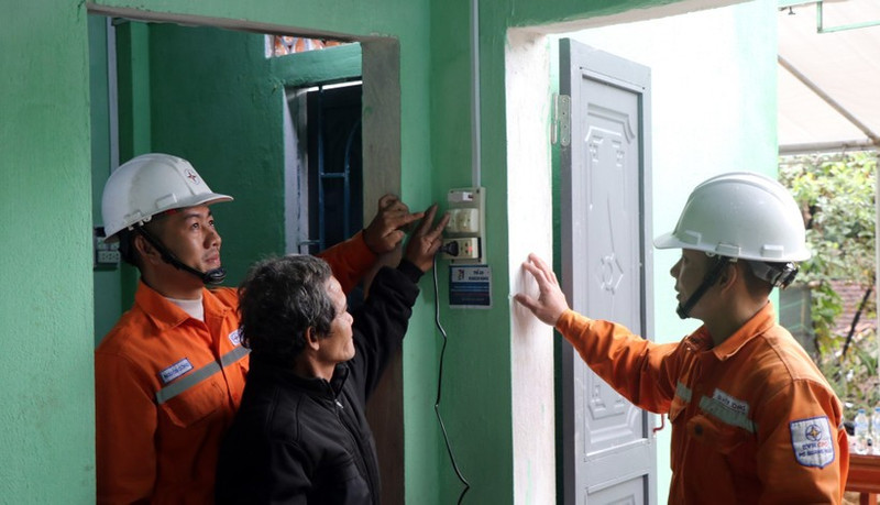 Electricistas enseñan a un residente equipos eléctricos en su nuevo hogar. (Foto: VNA)